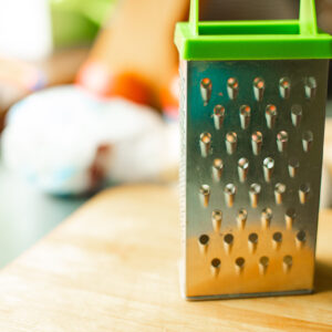 Picture of metal kitchen grater with oval holes on it on the kitchen table