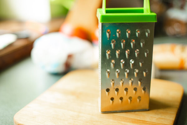 Picture of metal kitchen grater with oval holes on it on the kitchen table